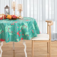 a table with a christmas themed table cloth on it and two candles in the background