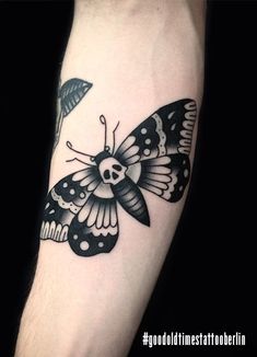 a black and white butterfly tattoo on the arm