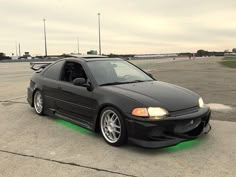 a black car parked on top of an airport tarmac with its hood up and lights on