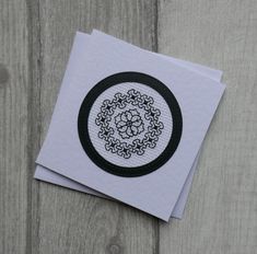 two cards with black and white designs sitting on top of each other next to a piece of paper