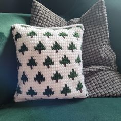 two crocheted pillows sitting on top of a green couch