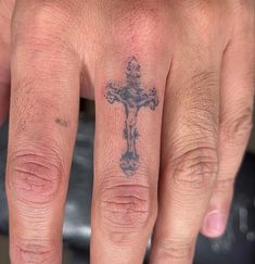 a hand with a cross tattoo on it