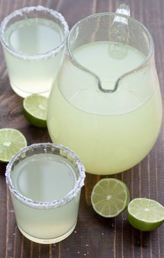 two glasses filled with lemonade next to limes