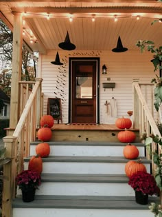 some pumpkins are sitting on the steps in front of a house that is decorated with lights