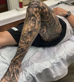 a woman laying on top of a bed with tattoos on her arm and leg,