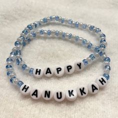 "Festive holiday bracelet set. Made with white and blue glass beads and white plastic alphabet letters that spell out \"HAPPY HANUKKAH\". Set includes 2 stretch bracelets, with each bracelet bearing one word. Beaded on stretch cord." Holiday Bracelet, Bracelet Message, Holiday Bracelets, Craft Board, Message Bracelet, Holiday Messages, Clay Bracelet, Holiday Craft, L Alphabet