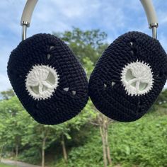 two black and white crocheted ear cushions hanging from a metal hook with trees in the background