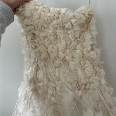 someone is holding up a dress made out of feathers and beads on the bottom part of it