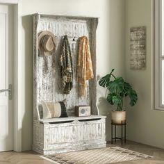 an old wooden coat rack with hats and coats hanging on it's sides next to a potted plant