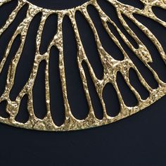 a gold necklace is shown on a black surface with an intricate design in the center