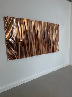 a white room with a large metal piece on the wall and a vase in front of it