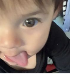 a young child making a funny face with his tongue hanging out and looking at the camera