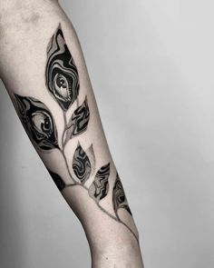 a black and white photo of a person's leg with an artistic tattoo design on it