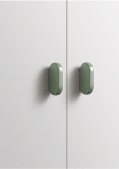 two green knobs are on the white cabinet doors and one is closed to let light in