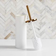 a white toilet brush sitting next to a white vase on top of a marble counter