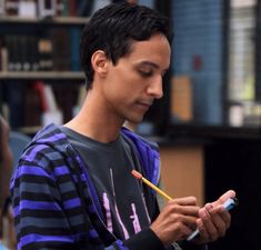 a young man holding a pencil and looking at his cell phone