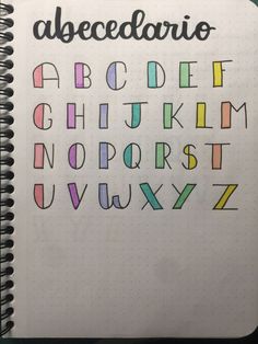 an open notebook with the alphabet written in different colors and shapes on top of it