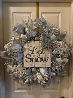 a wreath that says let it snow on the front door with silver and white decorations