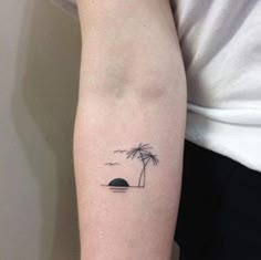 a small palm tree tattoo on the left arm