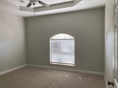 an empty room with a ceiling fan and window