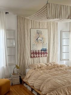 a large bed sitting under a window next to a painting on the wall in a bedroom