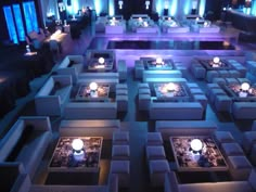 a room filled with lots of white couches covered in blue and purple lights at night