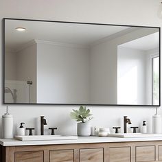 a bathroom with two sinks and a large mirror on the wall over it's counter