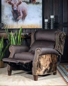 a living room with a cow print on the wall and leather recliners in front of it