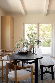 a dining room table with four chairs and a bench in front of the sliding glass doors