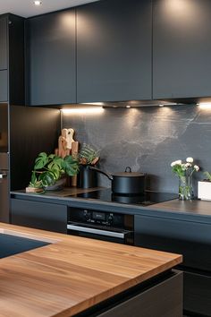 a kitchen with black cabinets and wooden counter tops, potted plants on the stove