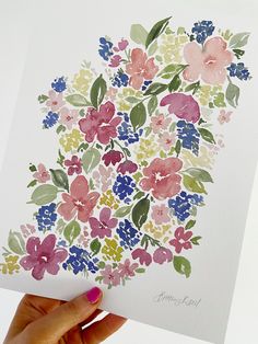 a person holding up a card with watercolor flowers on it