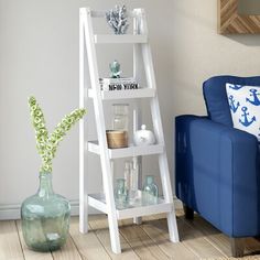 a living room with a blue couch and white ladder shelf next to it on the floor