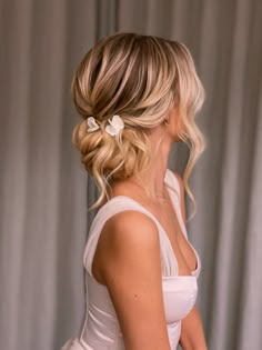 a woman with blonde hair wearing a white dress and flower in her hair, looking down