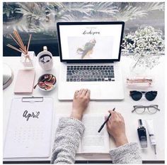 a person sitting at a desk with a laptop and notebook in front of them, surrounded by office supplies