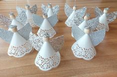 four white angel ornaments are sitting on a wooden table with silver sequins and wood beads