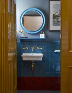 there is a sink and mirror in this bathroom with blue tiles on the walls, along with gold trimmings