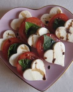 a heart shaped plate filled with sliced tomatoes and mozzarella