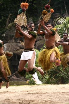 some men are dancing with hula skirts and headdresses in the air