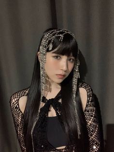 a woman with long black hair wearing a head piece