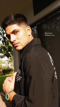 a young man in a black jacket is posing for the camera with his hand on his chest