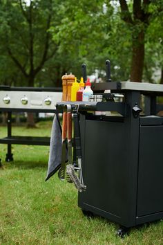 an outdoor bbq grill in the grass with towels hanging from it's handlebars