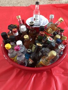 a red bowl filled with lots of bottles and condiments on top of a table