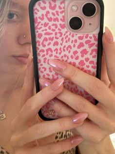 a woman holding up her phone case with pink leopard print