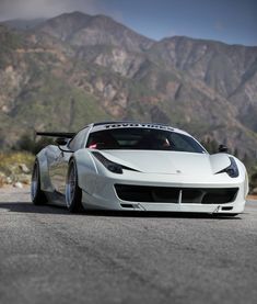 a white sports car parked in front of mountains