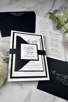 black and white wedding stationery on marble table with flowers in vases next to it