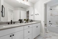 a white bathroom with marble counter tops and double sinks