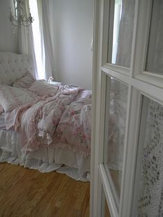 a white bed sitting next to a window in a bedroom under a chandelier