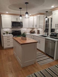 a kitchen with white cabinets and wooden counter tops, an island in between the stove and sink