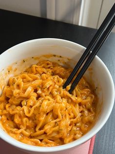 a white bowl filled with noodles and chopsticks