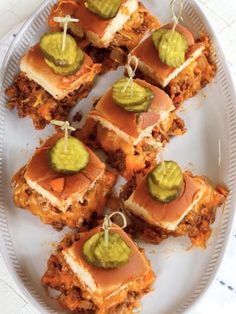 several small sandwiches on a white plate with sauce and guacamole garnishes